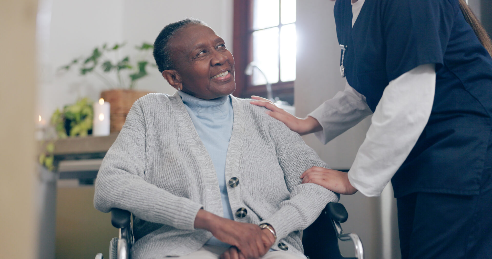 Healthcare provider in blue uniform supporting and encouraging senior woman with mobility challenges during home health care rehabilitation session